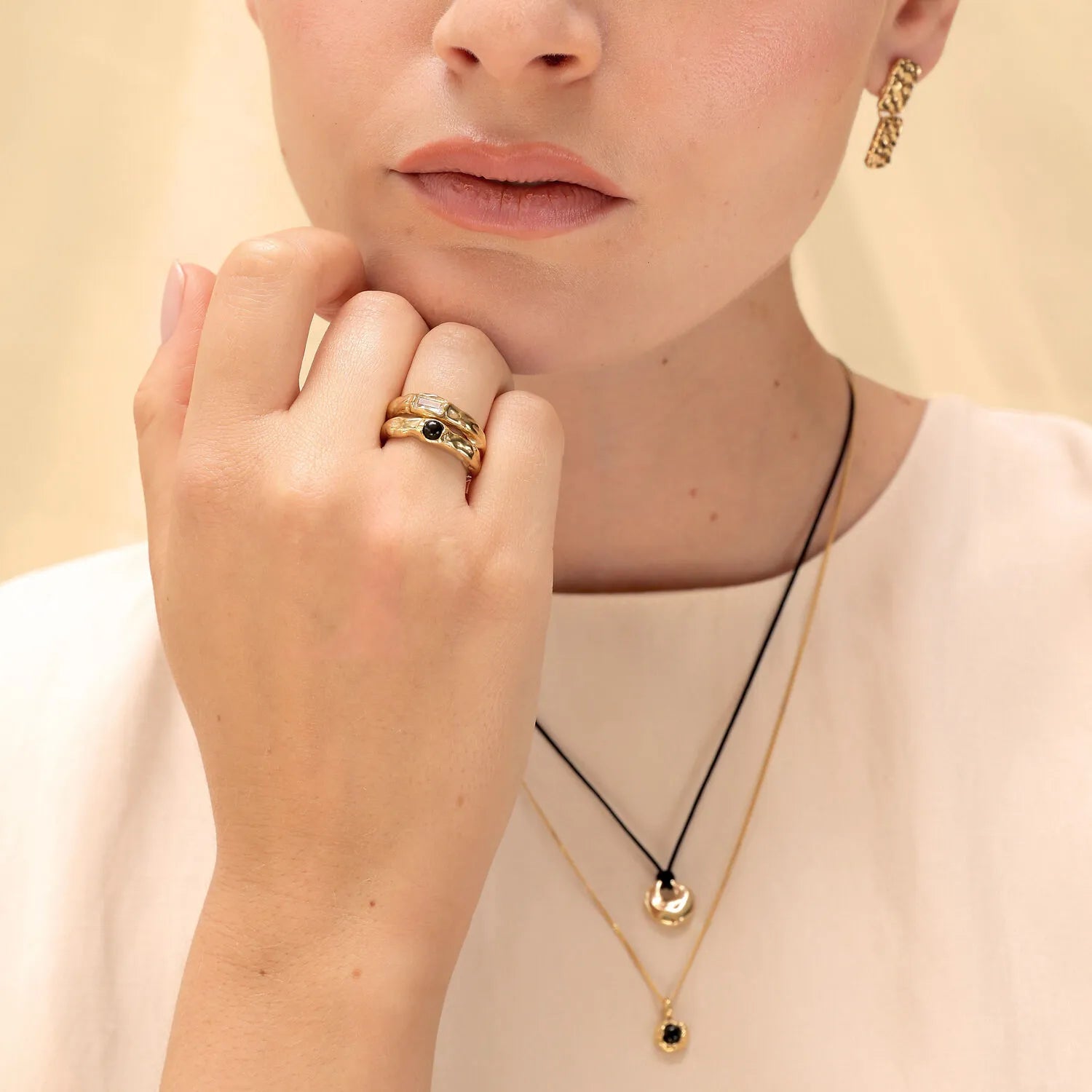Model trägt Ringset Melted mit Onyx und Topas, Nylonkette Disc Organic und Halskette Melted Anhänger in Gold
