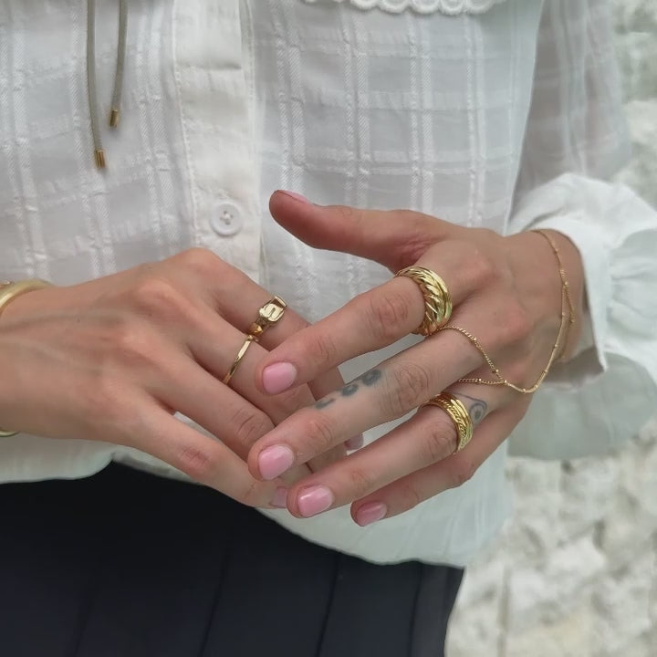 Goldenes Ringstack kombiniert mit einer Handkette